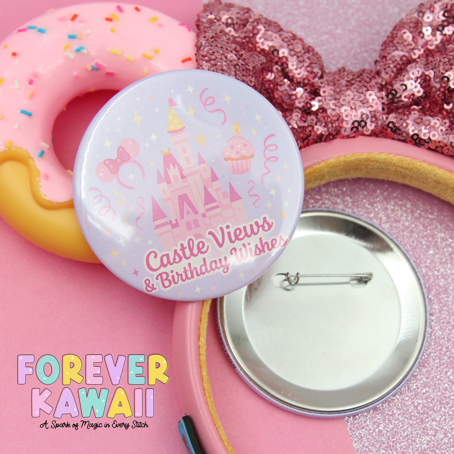 a pink button with a castle and cupcake design, along with a pink sequin bow and a pink sequin headband. The button is placed on a pink surface, and there is a silver pinback attached to it.