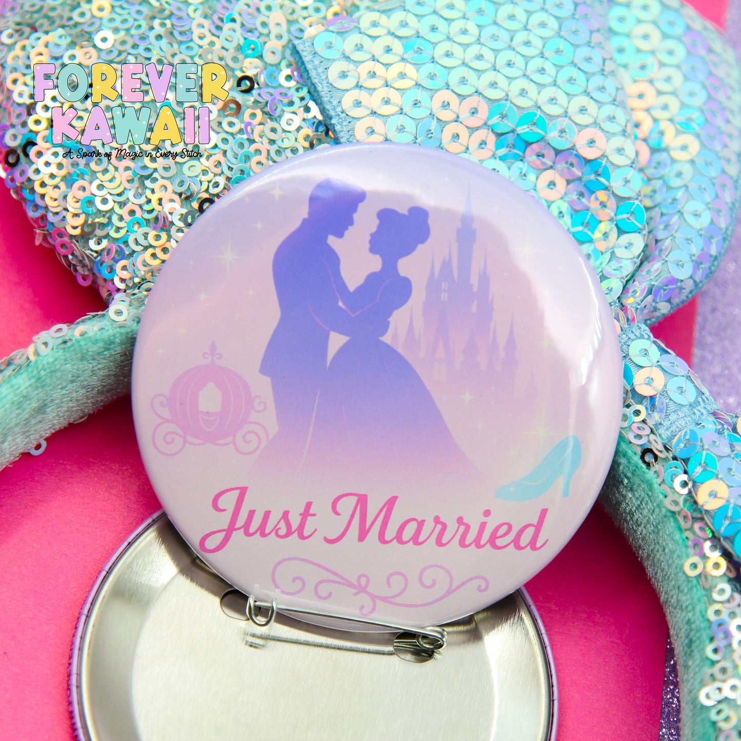 A button with a silhouette of a couple embracing, along with a castle and a carriage, and the text "Just Married" printed on it. The button is placed on a pink surface, and there is a sequined item in the background.