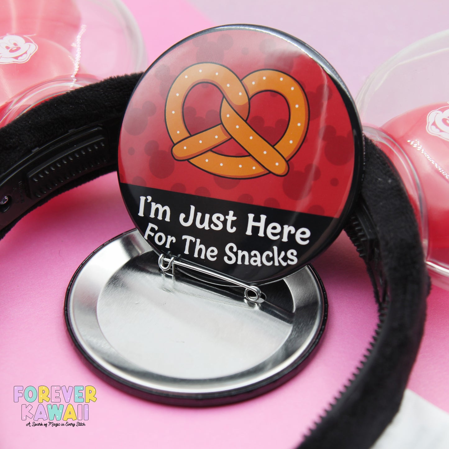 A red button with a pretzel graphic and the text "I'm Just Here for the Snacks" is shown, with a black band around it.