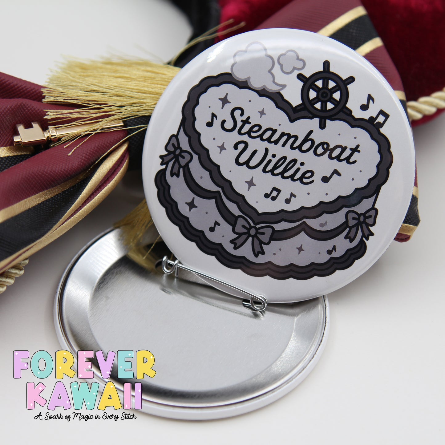 A round pin with a decorative design, featuring a steamboat and the text "Steamboat Willie" on it, placed on a silver stand.