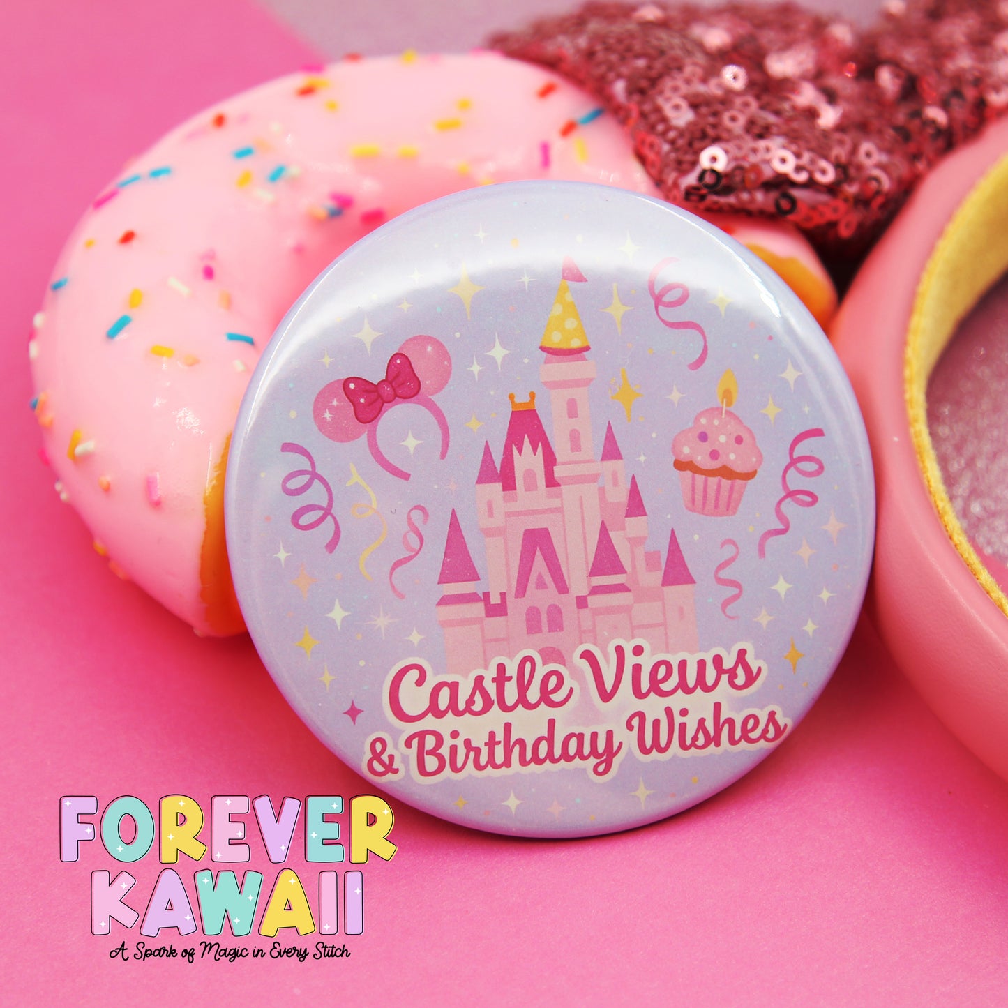 A pink donut with sprinkles, a pink cupcake, and a pink castle-themed button with the text "Castle Views & Birthday Wishes" on it, all set against a pink background.