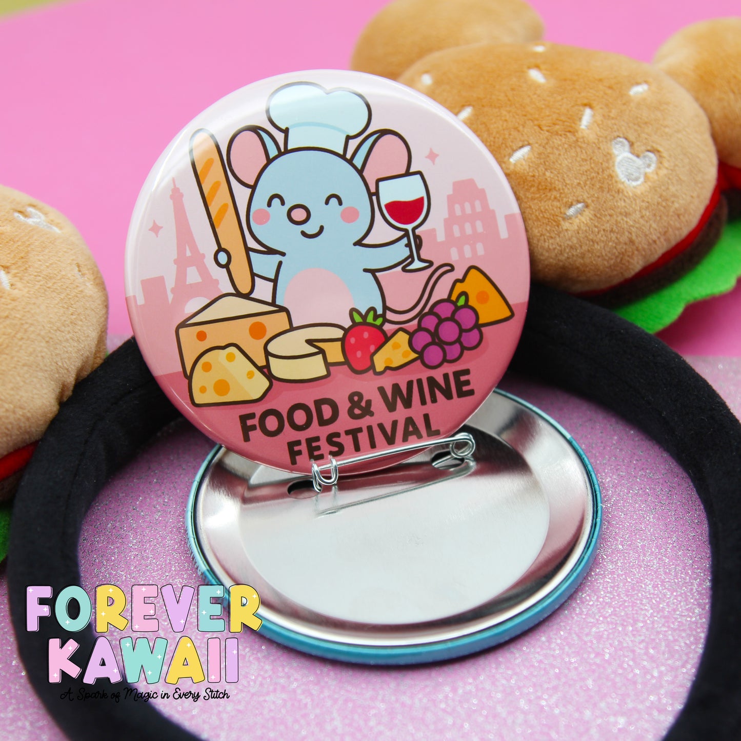 A round pin with a cartoon mouse chef and various food items, such as cheese, grapes, and a wine glass, is displayed on a pink background.