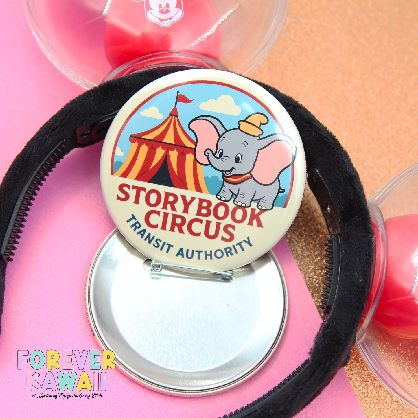 a round pin badge with a cartoon elephant and a circus tent, along with a black headband.