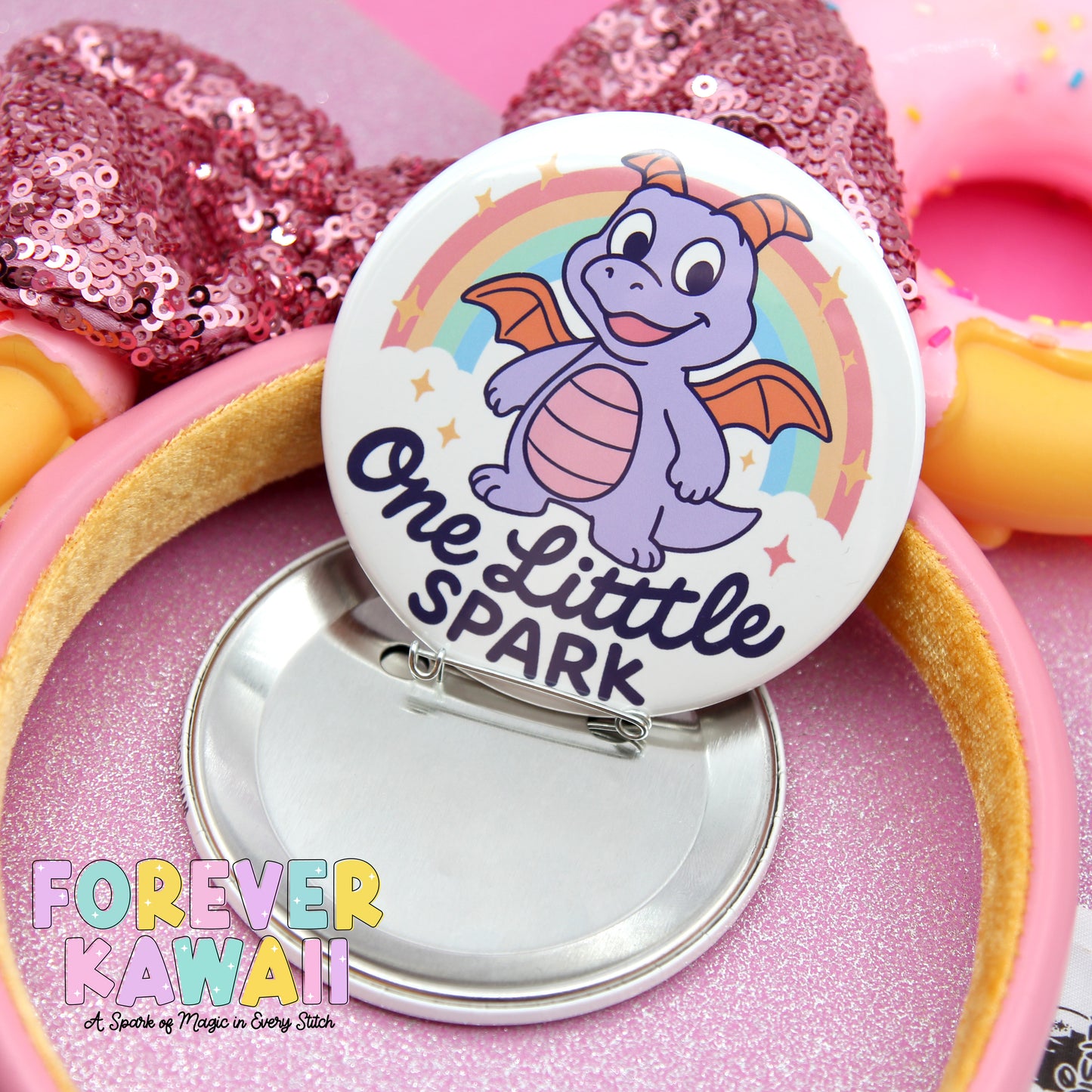 A pinwheel with a dragon and a rainbow, along with a pink sequin headband and a doughnut, all set against a pink background.