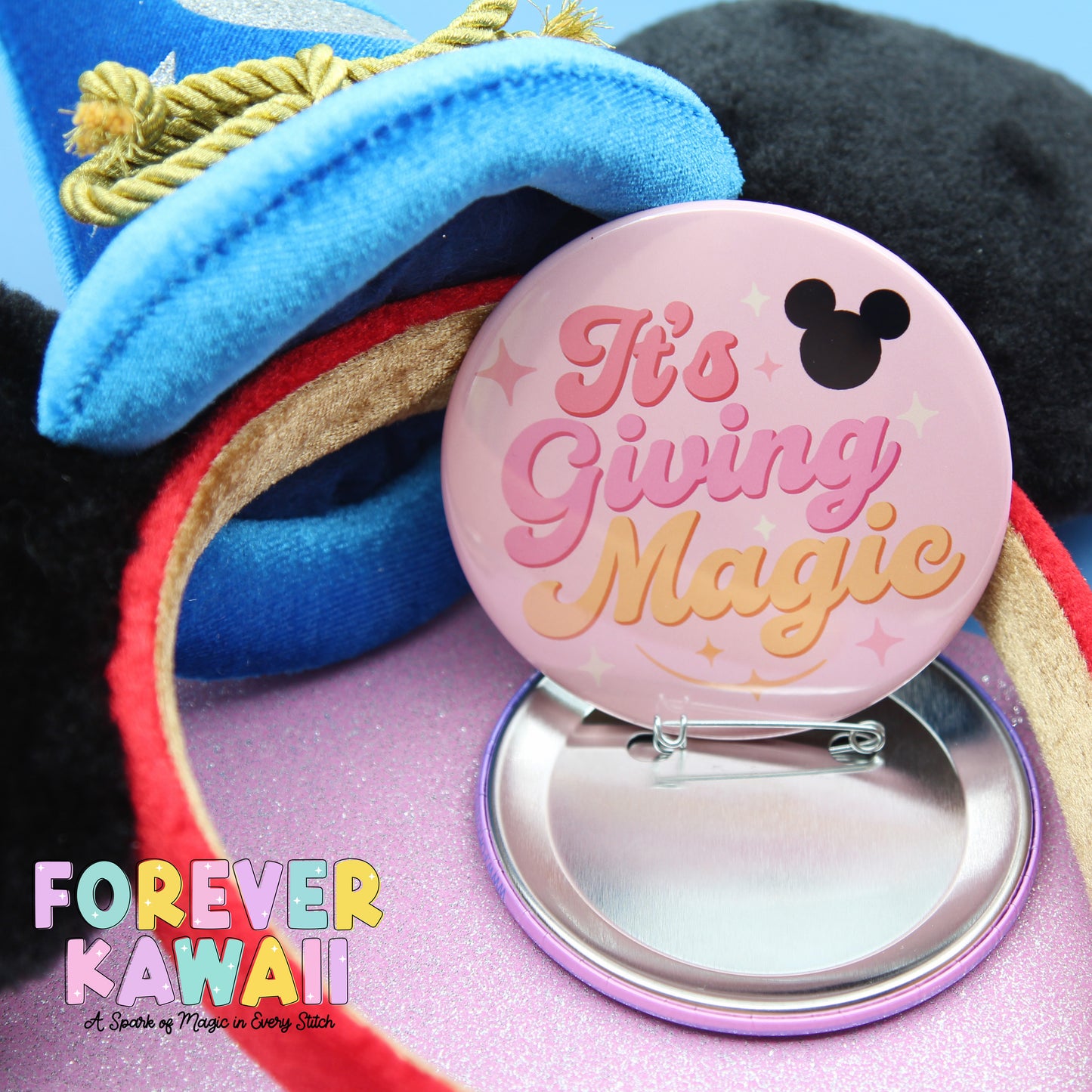 a pink pin with the text "It's Giving Magic" and a small black Mickey Mouse icon, placed on a pink surface.