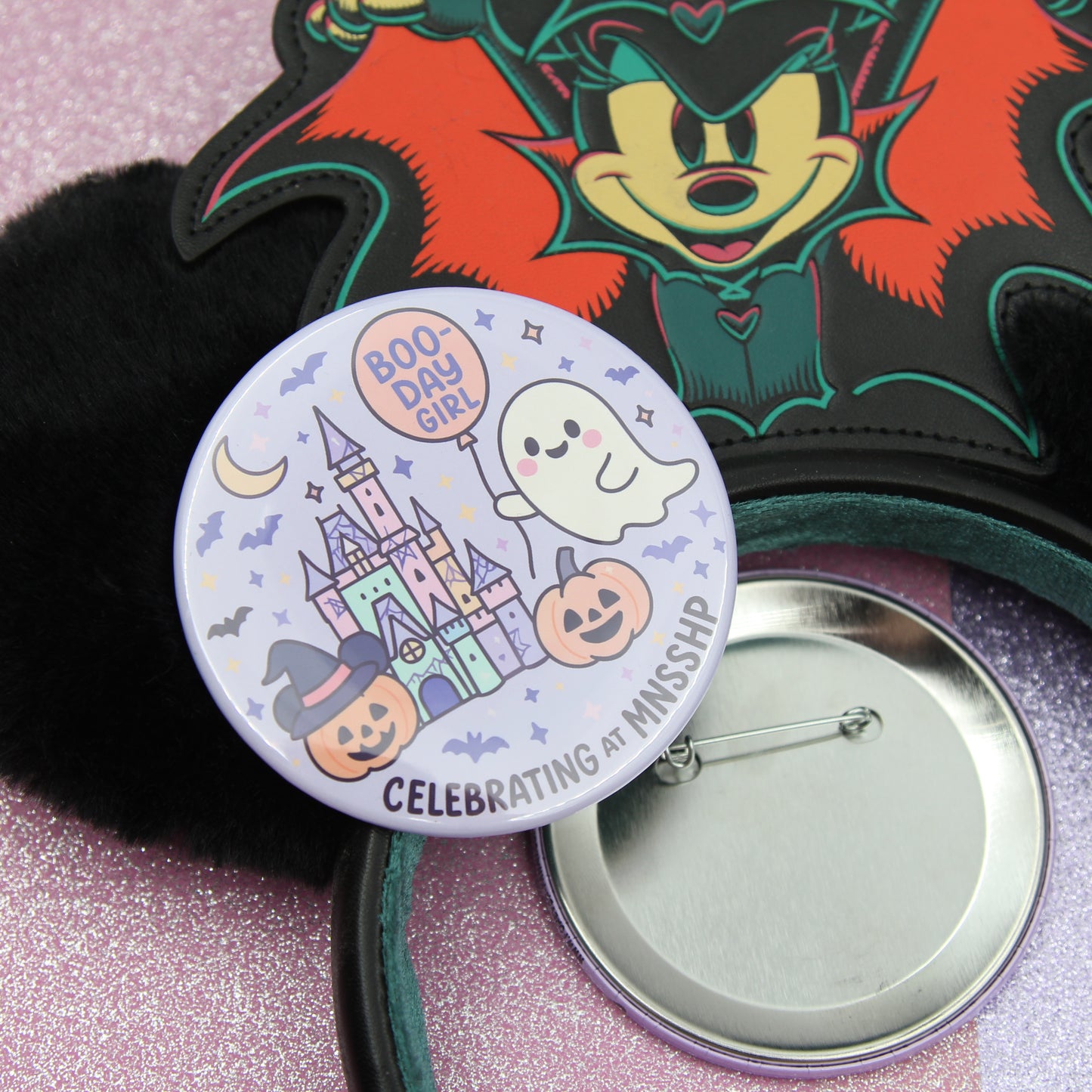 a Halloween-themed button and a black plush toy with a bat design.