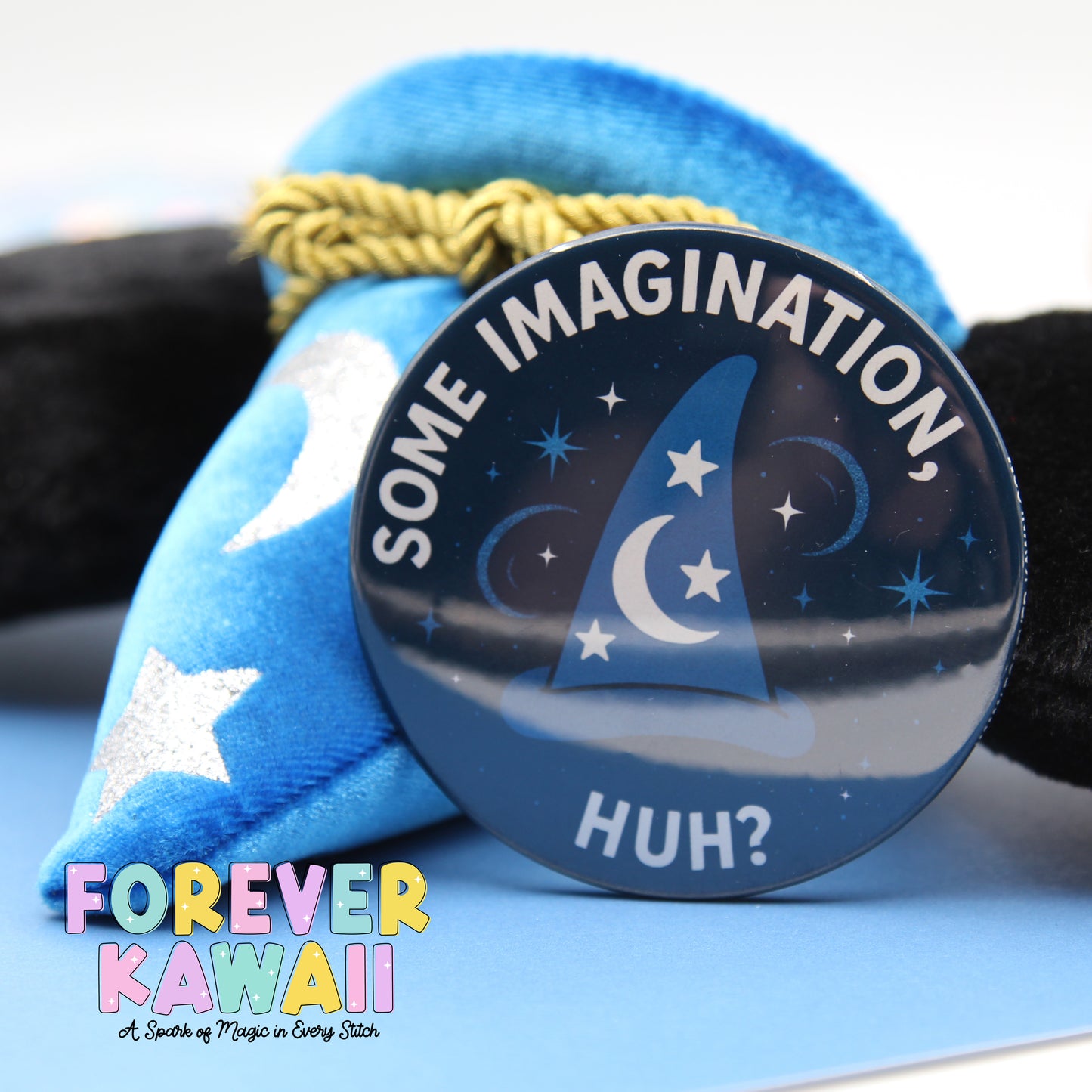 a blue wizard hat with a silver star and a round badge with the text "SOME IMAGINATION HUH?"