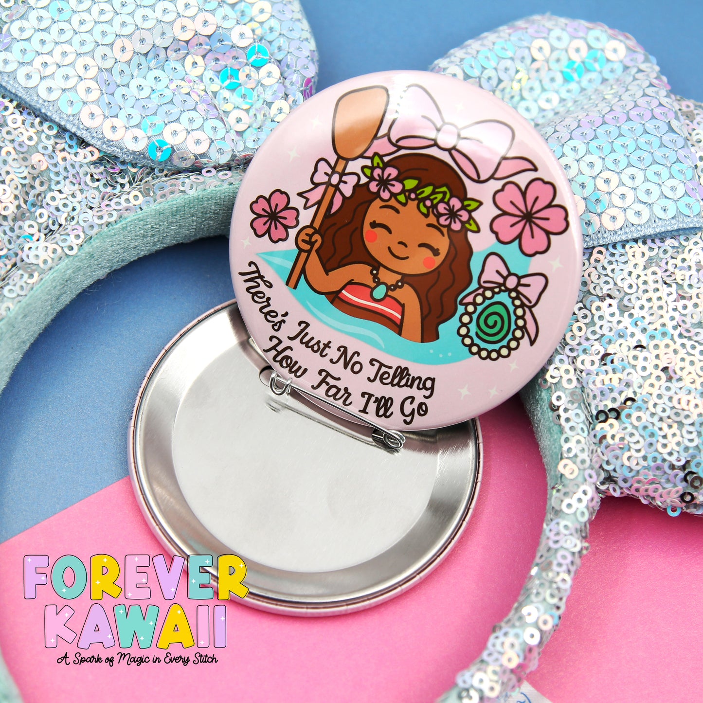 a round pin with a cartoon character on it, placed on a pink surface. The pin has a silver clasp and is surrounded by sequin earrings.