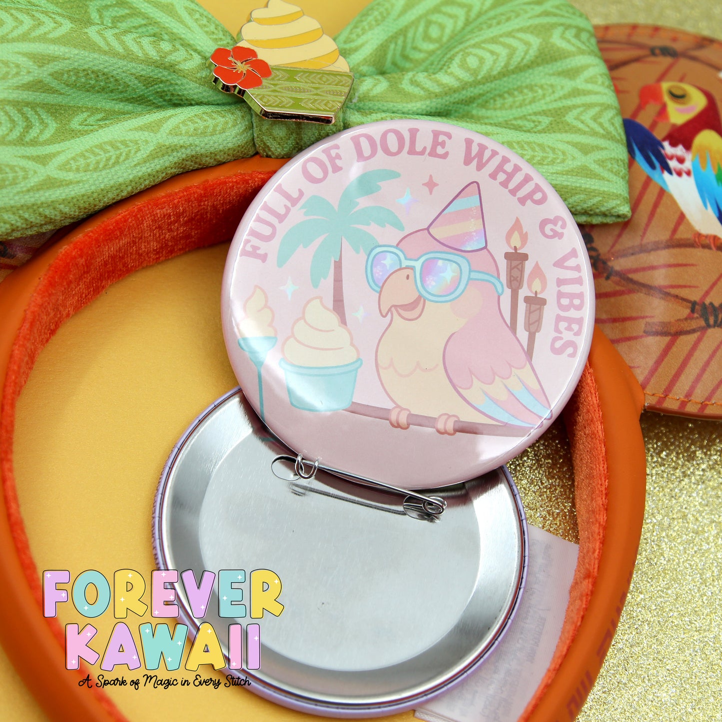 a pink pin with a cartoon bird and the text "Full of Dole Whip & Vibes" on it, along with a green bow and a red and yellow pin. The pin is placed on a yellow surface, and there is a green bow and a red and yellow pin in the background.