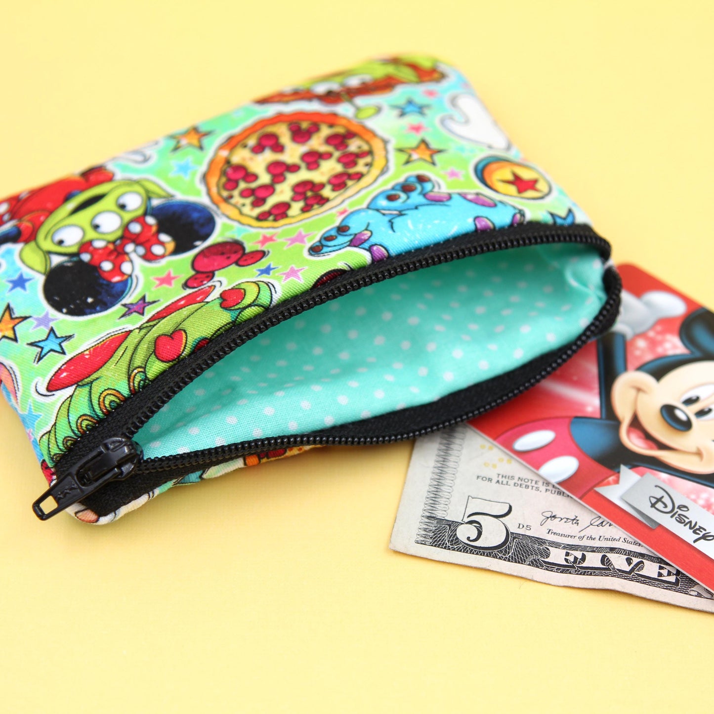 Handmade zipper pouch featuring a little green alien-inspired character dressed as various iconic Disney theme park characters, perfect for holding small essentials like coins, cards, and cash.