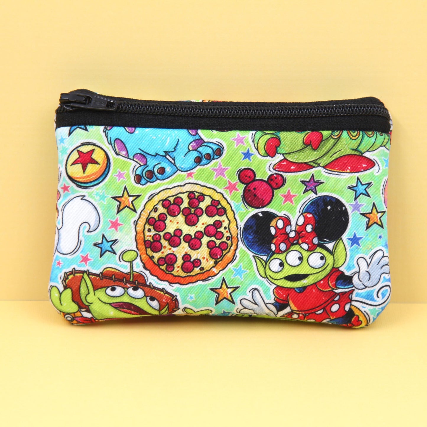 Handmade zipper pouch featuring a little green alien-inspired character dressed as various iconic Disney theme park characters, perfect for holding small essentials like coins, cards, and cash.