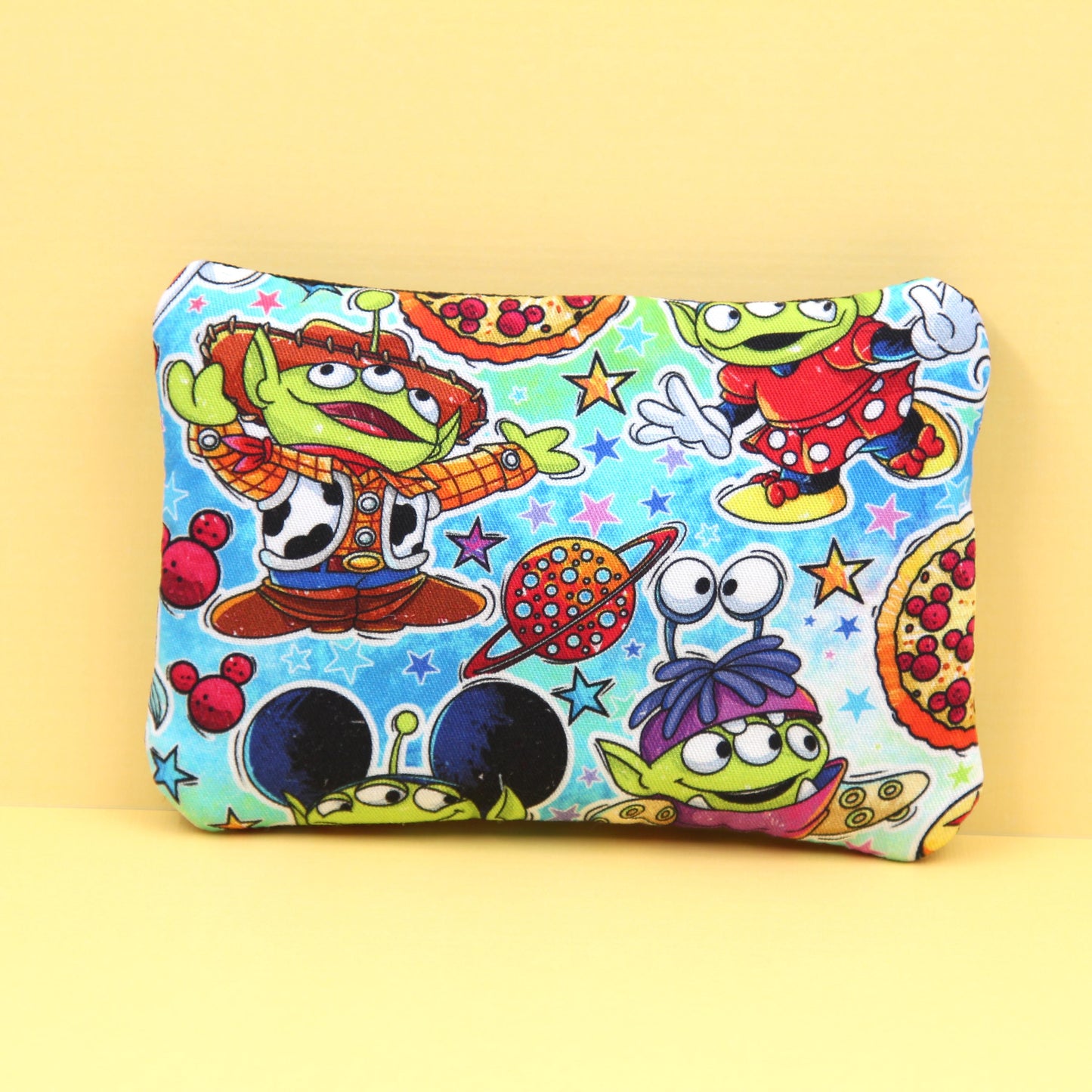 Handmade zipper pouch featuring a little green alien-inspired character dressed as various iconic Disney theme park characters, perfect for holding small essentials like coins, cards, and cash.