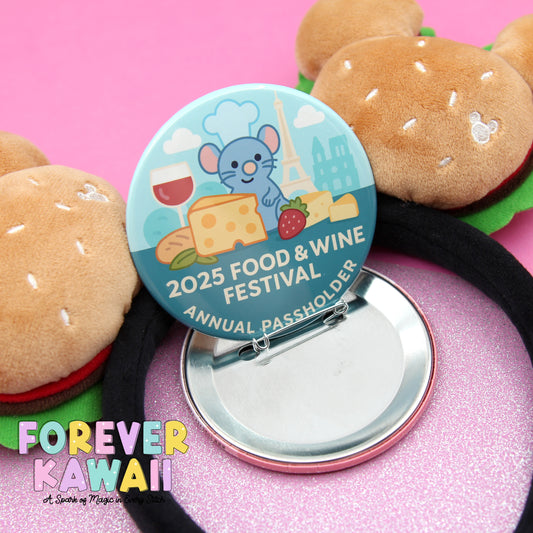 A circular button with a cartoon mouse and various food items, such as cheese, bread, and a wine glass, is placed on a pink background. There are also two stuffed animal hamburgers and a black hairband visible in the image.