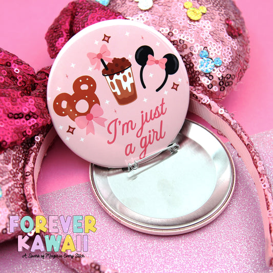 a pink button with a playful design, including a cupcake, a pair of Mickey Mouse ears, and the text "I'm just a girl". The button is placed on a pink sequin headband, and there is a pink background with the text "FREVER KAWAI" and "A Spark of Magic in Every Stitch" written below the button.