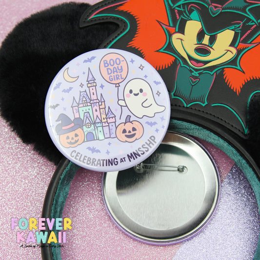 a Halloween-themed button with a cartoon character and a ghost, along with a pinwheel and a black furry object.