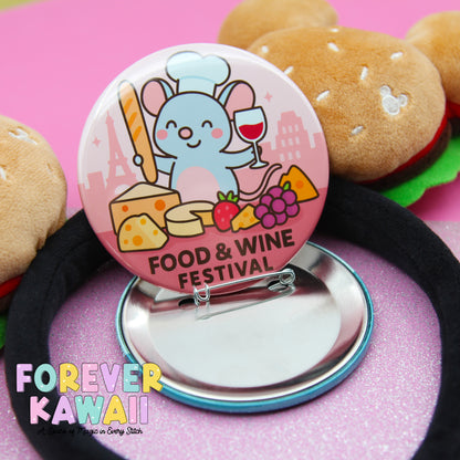 A round pin with a cartoon mouse chef and various food items, such as cheese, grapes, and a wine glass, is displayed on a pink background.