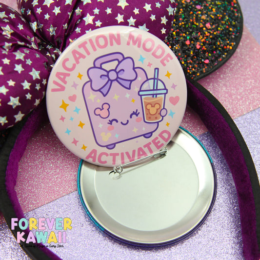 a pink button with a cartoon character and the text "VACATION MODE ACTIVATED" on it, along with a purple bow and a straw. The button is placed on a purple glittery surface, and there is a purple headband in the background.