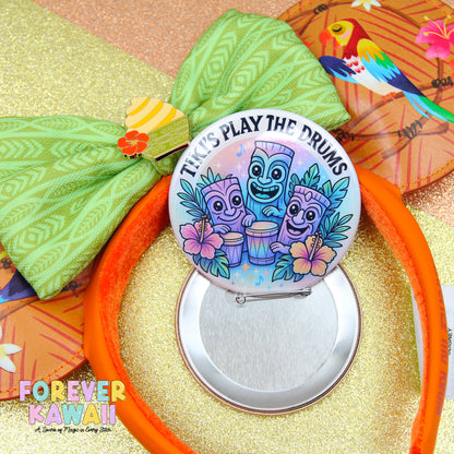 a colorful pinwheel with a tiki drum design, surrounded by a green bow and a tiki mask.
