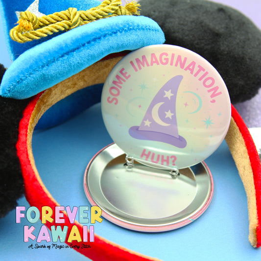 A round pin with a wizard hat and the text "Some Imagination. Huh?" is placed on a silver stand, surrounded by a blue background and a red ribbon.