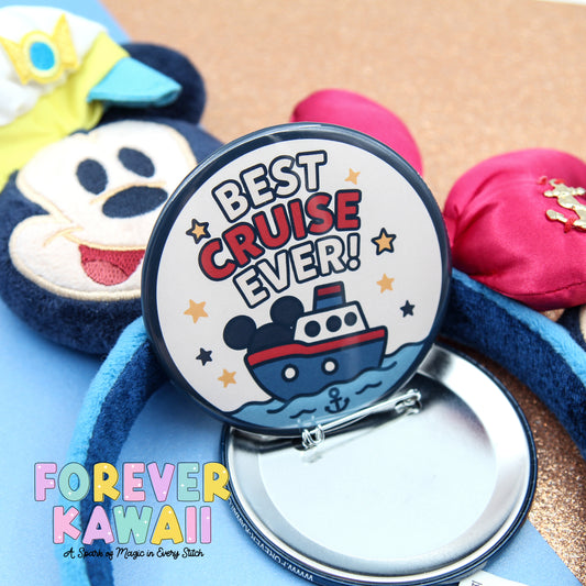 A round pin with a cartoon image of a ship and the text "BEST CRUISE EVER!" is displayed on a blue background, along with a Mickey Mouse hat and other Disney-themed items.