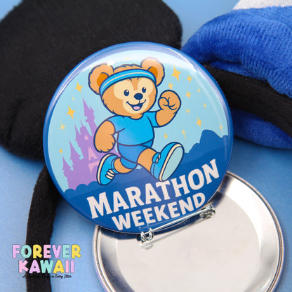A round pin with a cartoon bear running and the text "Marathon Weekend" on it, along with a blue background and a castle illustration.