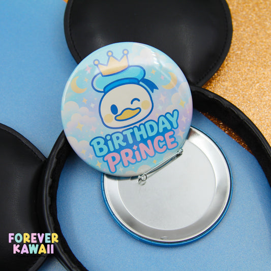 A birthday pin with a cartoon duck wearing a crown and the text "Birthday Prince" is shown, along with a black button and a blue background.