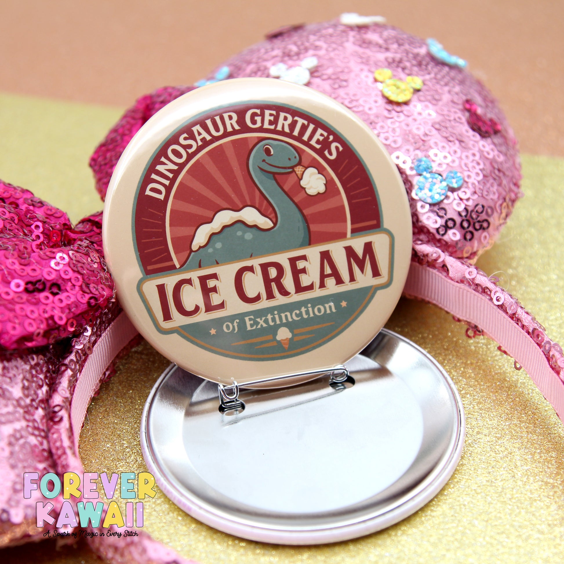 A round badge with the text "DINOSAUR GERTIE'S ICE CREAM of Extinction" and a dinosaur illustration, placed on a pink sequin headband.