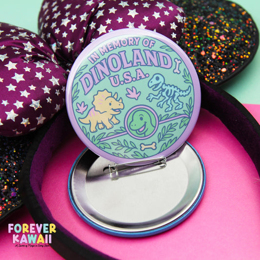 A round pin with a design featuring a dinosaur and other cartoon-like elements, placed on a pink surface.